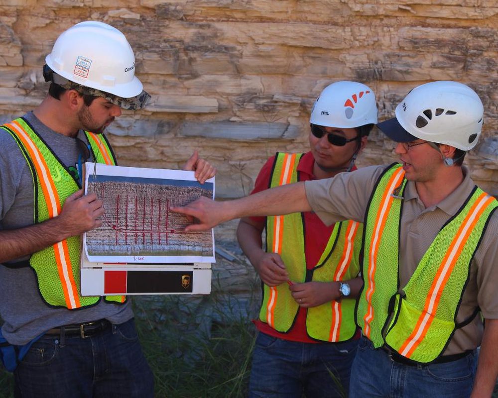 Project team in safety gear reviewing building plans together on site