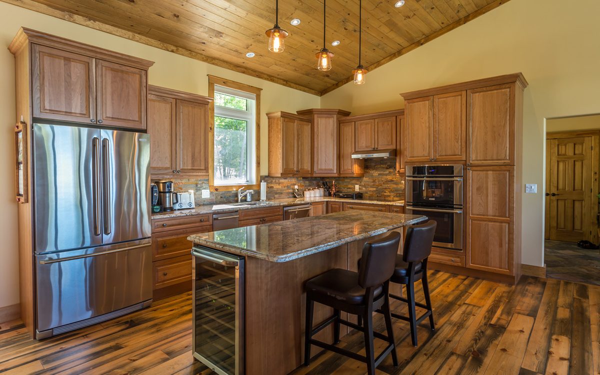 Kitchen with warm wood cabinets, a stone topped island, bar stools and pendant lights