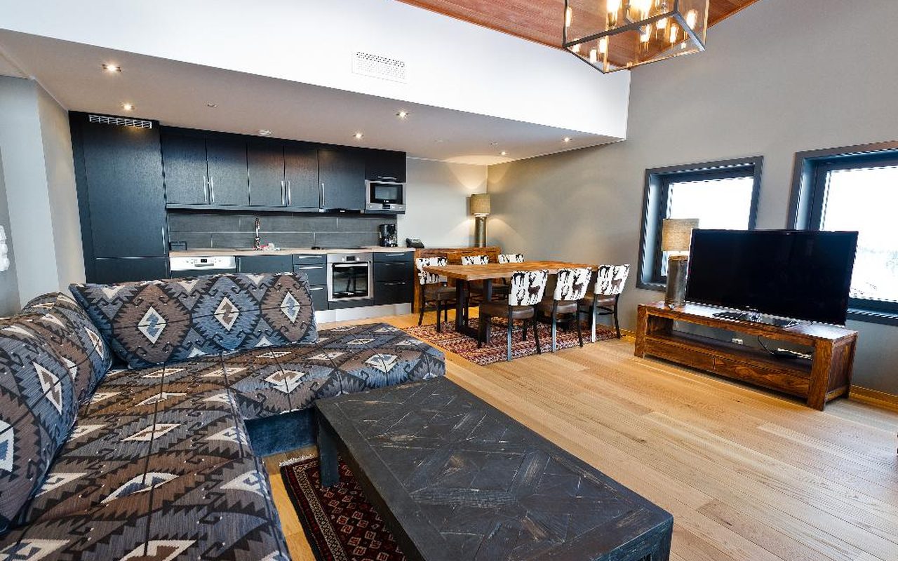 Open plan living room with a patterned sectional sofa, wood floors and a modern kitchen