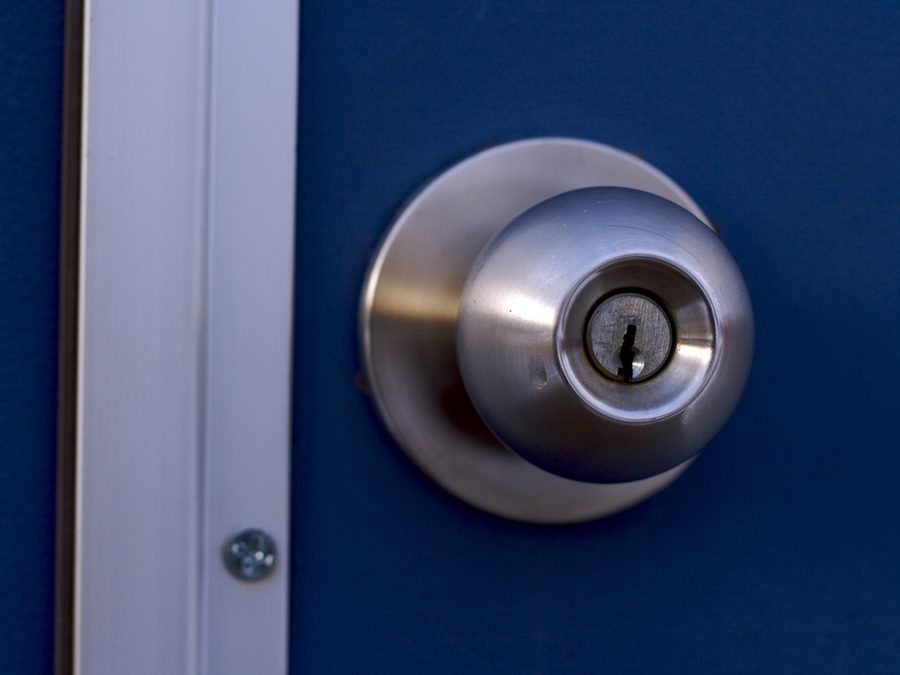 Brushed steel keyed door knob on a deep blue front door