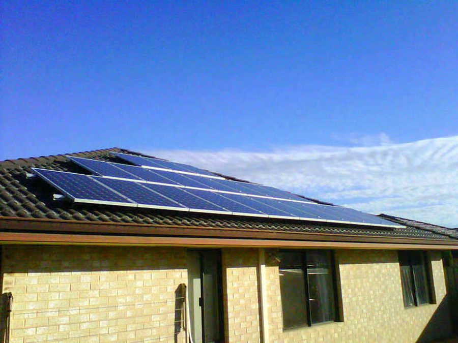Solar panels on a tiled house roof under a clear blue sky
