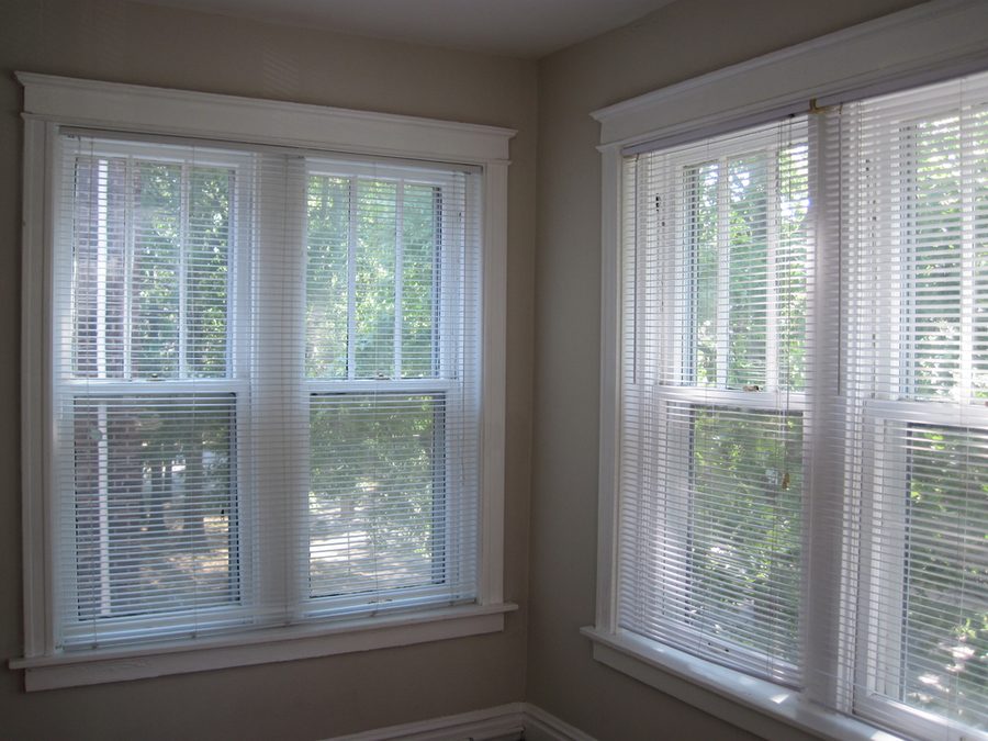 Sunroom corner with tall white double hung windows and blinds